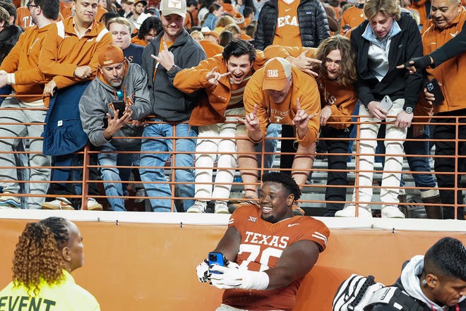 Texas Longhorns offensive lineman Christian Jones (70) takes a selfie with fans following the game against Texas Tech at Darrell K Royal Texas Memorial Stadium on Friday, Nov. 24, 2023.